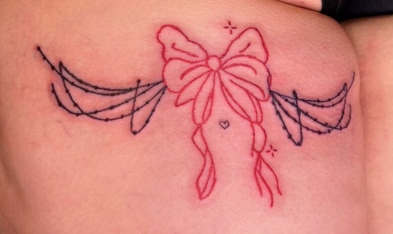 A pink ribbon bow in the middle of two swags of black barbed wire