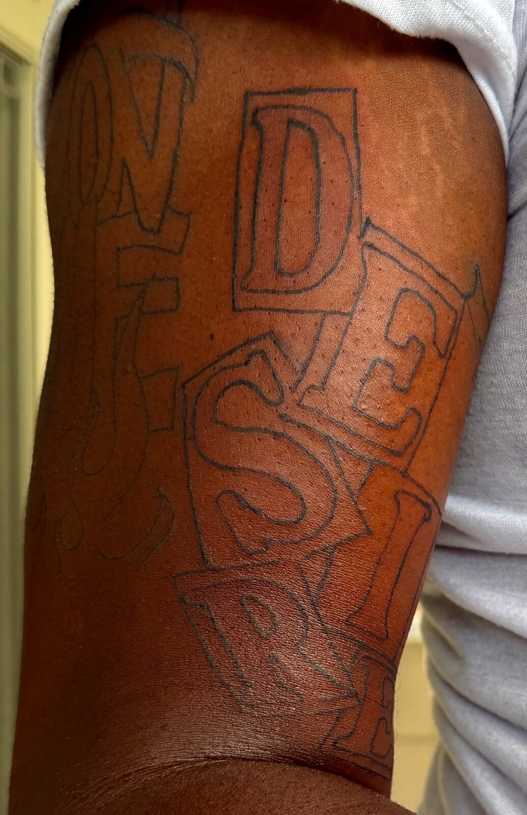 Large outlined block letters tumbling down the upper arm