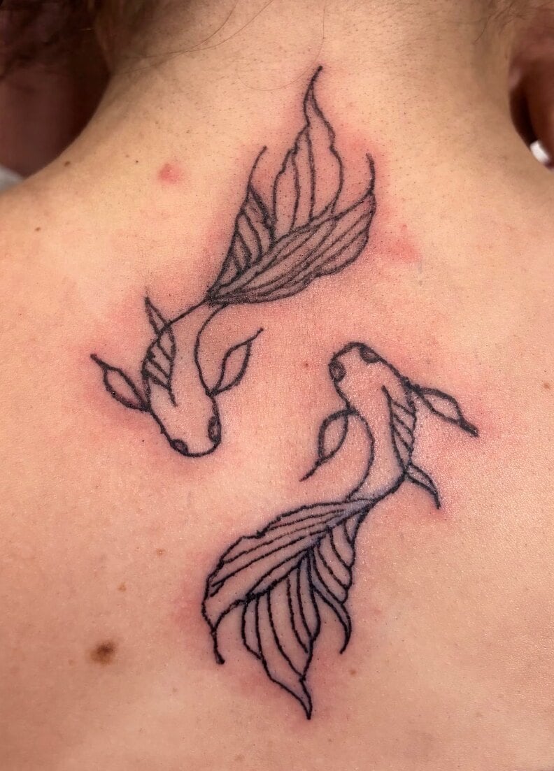 Two koi fish circling each other in black linework below the nape of the neck