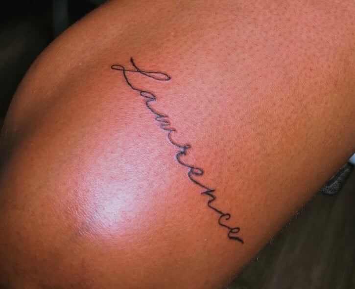 A name in flowing single-line script running diagonally above the knee