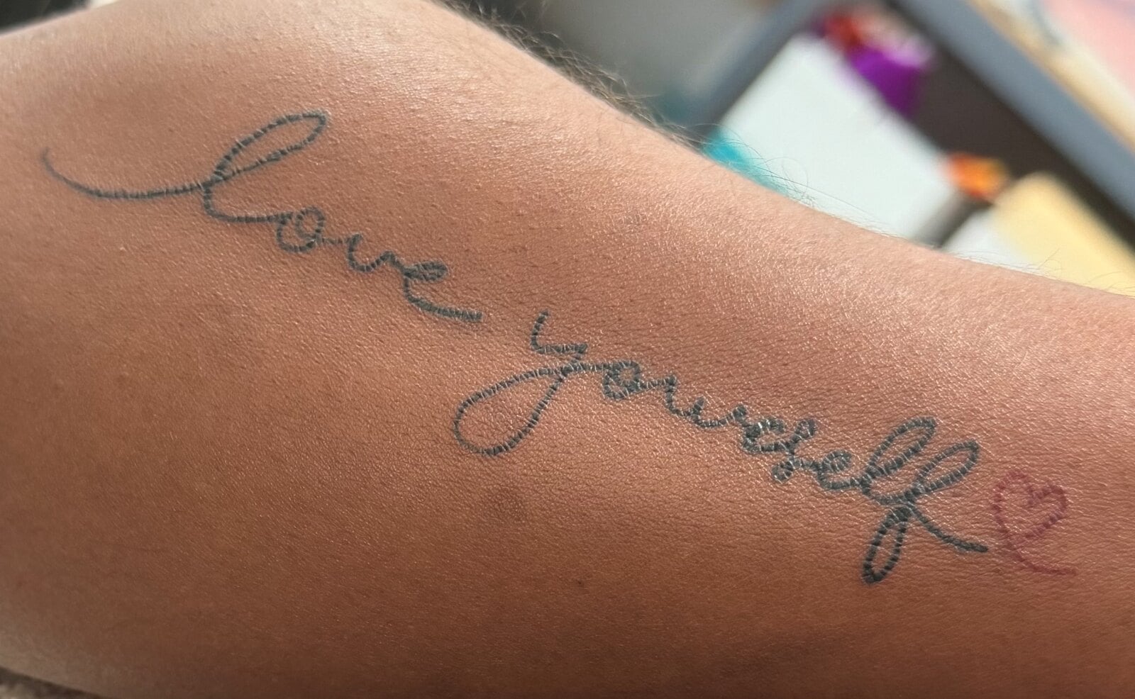 The words love yourself in looping script, finished with a small red heart